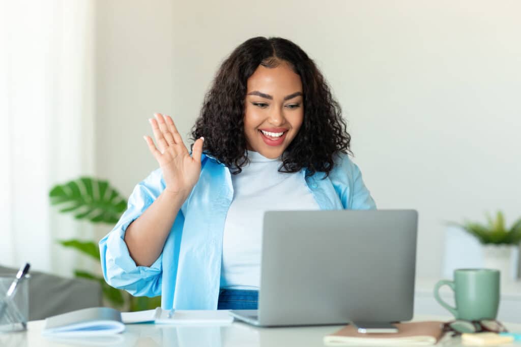 Online meeting concept. Happy black body positive lady using laptop for virtual conferencing, having video call at home. Cheerful woman communicating with colleagues or friends