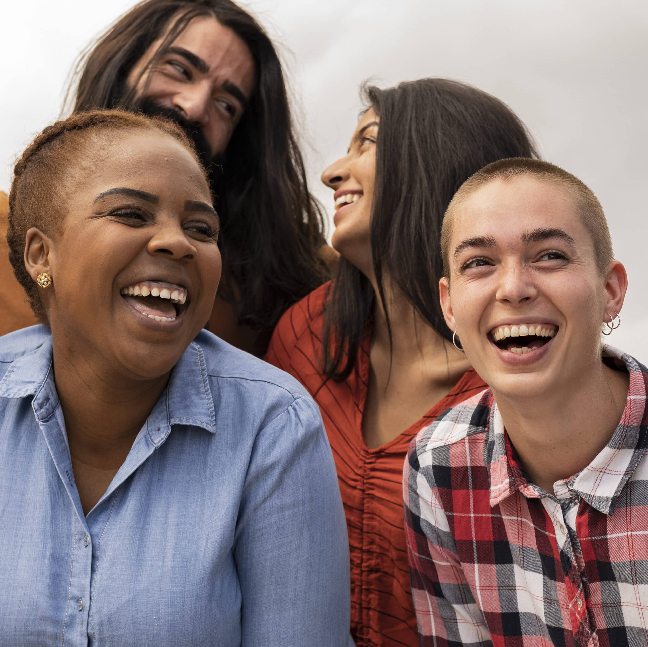 Large group of multiracial young adult friends having fun outdoors and smiling